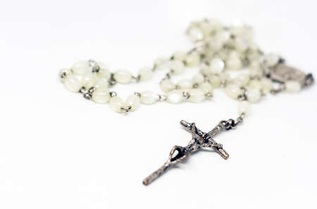 White pearl rosary with silver crucifix isolated on a white background. Prayer and devotion....