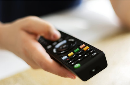 Caucasian woman hands holding television remote control. Selective focus. Infrared wireless...