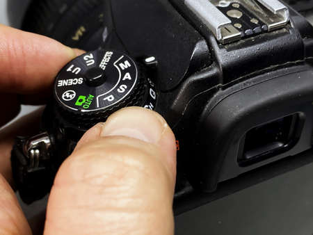 photographer turning the cogwheel to select the correct camera setting to take a picture. Buttons and settings of a digital DSLR camera.の写真素材