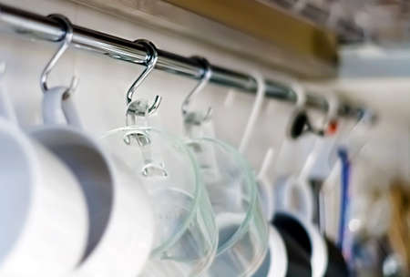 A set of mugs hanging on hooks in a modern home kitchen. Everyday objects. Domestic life.の写真素材