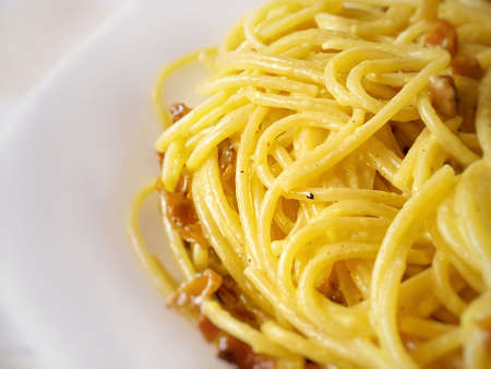Close up of cooked spaghetti with carbonara sauce. Traditional recipe of Italian cuisine. Cooked pasta with yellow carbonara egg yolk sauceの写真素材