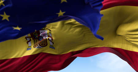 The national flag of Spain waving in the wind together with the European Union flag blurred in the foreground. Politics and finance. Spain is a member state of the European Unionの写真素材
