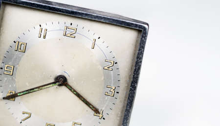 Old worn clock with square dial isolated on a white background. Analog time measurement. Vintage and retro object. Copy space.の写真素材