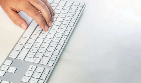 a male hand typing on a modern computer keyboard. Work and employment. Copy space. Wireless technologyの写真素材