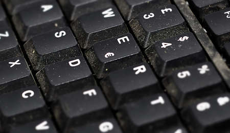 Detail of the buttons of a dusty black plastic european computer keyboard. Technology and computers....