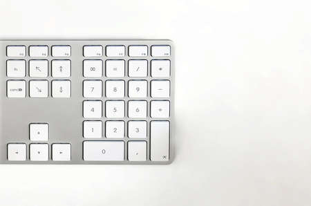 Detail of a modern white computer keyboard on a white table. Computer hardware device. Technology...