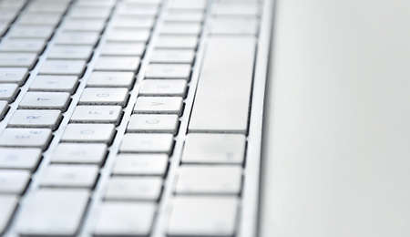 Detail of a modern white computer keyboard dirty and dusty on a white table. Computer hardware...