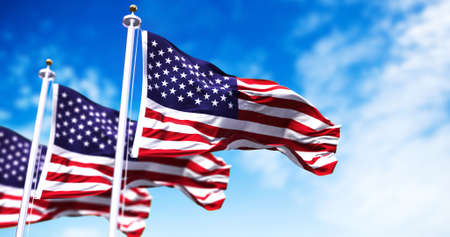 Three flags of the United States of America waving in the wind. Clear sky in the background....