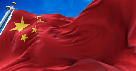 The national flag of People's Republic of China flying in the wind with a clear sky in the backgroundの写真素材