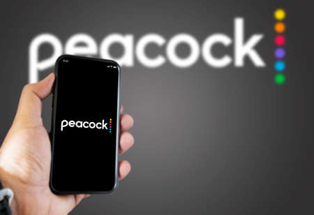 New York, USA, September 2021: hand holding a phone with the Peacock Tv mobile app on the screen and...
