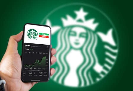New York, USA, November 2021: Hand holding a phone with Starbucks corp. stock chart and buy and sell...