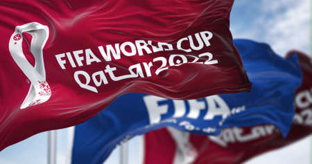 Doha, Qatar, April 2022: Flags with Qatar 2022 World Cup logo and FIFA waving in the wind. The event...