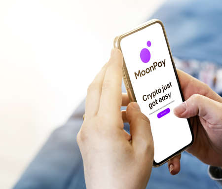 London, UK, March 2022: unrecognizable young female surfing on MoonPay website with a phone in her...