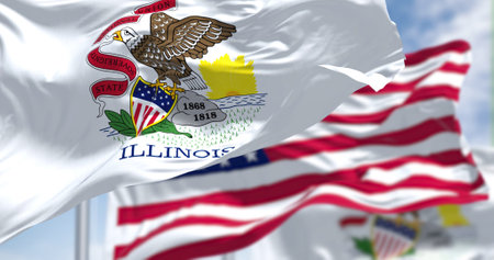 The Illinois state flag waving along with the national flag of the United States of America. In the...