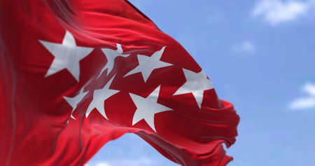 The Community of Madrid flag waving in the wind on a clear day. The Community of Madrid is one of...