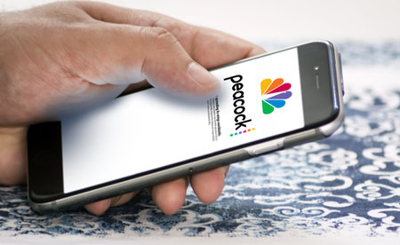 New York, USA, May 2022: hand holding a phone with the Peacock Tv mobile app on the screen. Peacock...