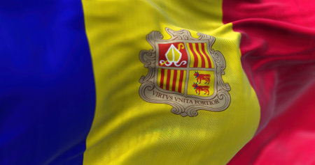 Close-up view of the andorran national flag waving in the wind. Andorra is a sovereign landlocked microstate on the Iberian Peninsula. Fabric textured background. Selective focusの写真素材
