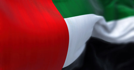 Close-up view of the United Arab Emirates national flag waving in the wind. The Emirates is a country in Western Asia. Fabric textured background. Selective focusの写真素材