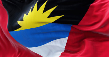 Close-up view of the Antigua and Barbuda national flag waving in the wind. Antigua and Barbuda is a sovereign island country of the West Indies. Fabric textured background. Selective focusの写真素材