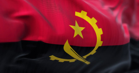 Close-up view of the Angola national flag waving in the wind. The Republic of Angola is a country located on the west coast of Southern Africa. Fabric textured background. Selective focusの写真素材