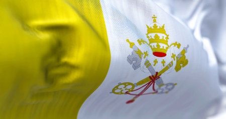 Close-up view of the Vatican City national flag waving in the wind. The Vatican City State is the...