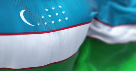 Close up view of the Uzbekistan national flag waving in the wind. The Republic of Uzbekistan is a country located in Central Asia. Fabric textured background. Selective focus. 3D illustrationの写真素材