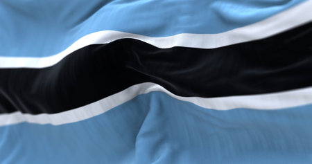 Close-up view of the Botswana national flag waving in the wind. The Republic of Botswana is a country in Southern Africa. Fabric textured background. Selective focus. Realistic 3d illustrationの写真素材
