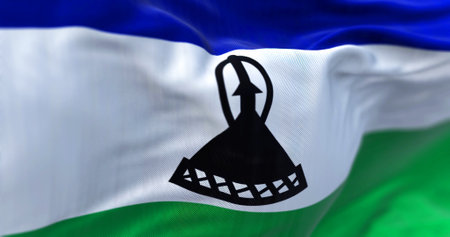 Detail of the Lesotho national flag waving. Horizontal blue, white, and green with a black mokorotlo in the center. Rippled fabric. Textured background. 3d illustration. Close-up. Selective focusの写真素材