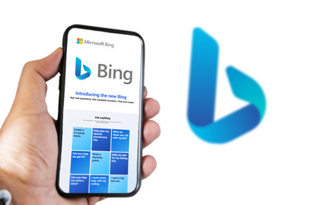 Redmond, US, Feb 2023: A hand holding a phone with the Microsoft Bing website on the screen. White...