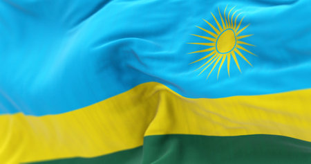 Detail of the Rwanda national flag waving. 3 horizontal bands: blue, yellow, green with 24 rays yellow sun. 3d illustration render. Selective focus. Close-up. Textured fabric backgroundの写真素材