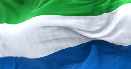 Detail of the Sierra Leone national flag waving in the wind. Tricolor with horizontal stripes in green, white and blue. Fabric textured background. Selective focus. 3D illustration render. Close-upの写真素材