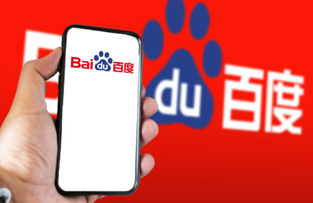 Beijing, CN, Feb 2023: A hand holding a phone with the Baidu website on the screen. Red background with blurred Baidu logo. Baidu is a Chinese multinational technology companyのeditorial素材