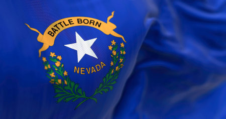 Nevada state flag waving. Blue background, white star, "Battle Born" ribbon, green branches with yellow sagebrush flowers. 3d illustration render. Close-up. Selective focus. Fluttering textileの写真素材