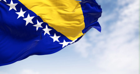 Flag of Bosnia and Herzegovina waving in the wind. Blue field with yellow triangle and white stars. 3d illustration render. Fluttering textileの写真素材