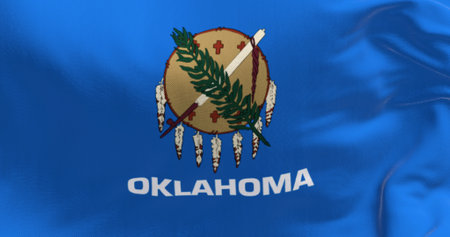 Detail of the the Oklahoma state flag waving. Blue field with a buffalo-skin shield, olive branch and peace pipe. Textured background. 3d illustration render. Close-up. Fluttering textileの写真素材
