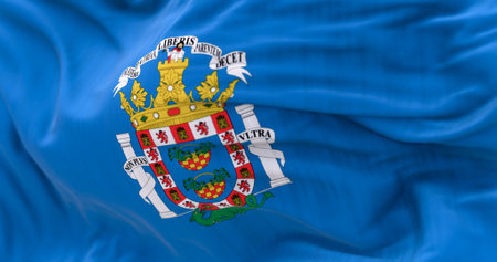 Detail of the Melilla flag waving. Autonomous city of Spain. Pale blue background with city coat of arms in the center. 3d illustration render. Selective focus. Close-up. Fluttering fabricの写真素材