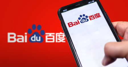Beijing, CN, Feb 2023: A hand holding a phone with the Baidu website on the screen. Red background with blurred Baidu logo. Baidu is a Chinese multinational technology company. Illustrative editorialのeditorial素材
