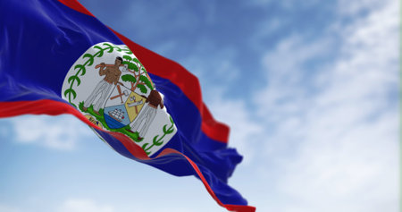 Belize national flag waving in the wind on a clear day. Blue field, red stripes top and bottom,...
