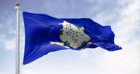 The Connecticut state flag waving on a clear day. White shield on blue background featuring three grapevines each bearing bunches of grapes. Textured background. 3d illustration renderの写真素材