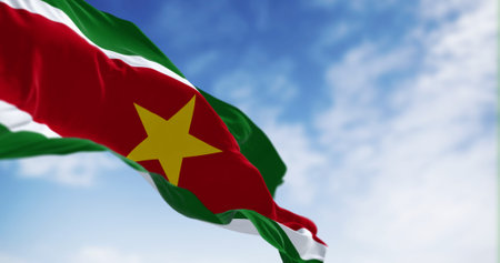 Suriname national flag waving in the wind on a clear day. 5 horizontal bands: green, white, red, white, green, yellow star in the center. 3D illustration render. Fluttering textile. Selective focusの写真素材