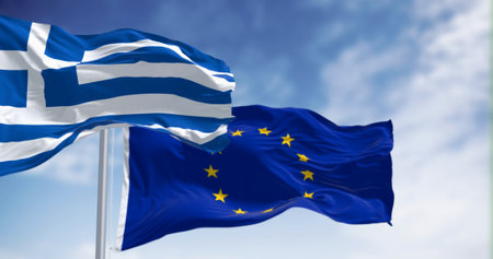 The flags of Greece and the European Union waving together on a clear day. Greece became a member of...