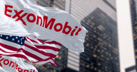 Spring, US, Oct. 5 2023: ExxonMobil and the American flags waving in the wind in a financial district. American multinational oil and gas corporation. Illustrative editorial 3d illustration renderのeditorial素材
