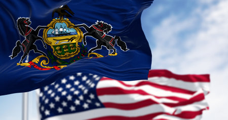 Pennsylvania state flag waving with the american flag. Blue field with state coat of arms: shield...