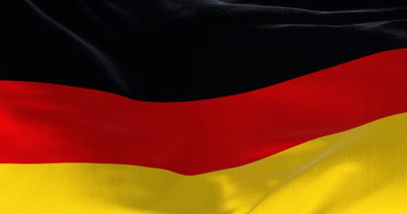 Close-up of Germany national flag waving in the wind on a clear day. Three horizontal bands of...