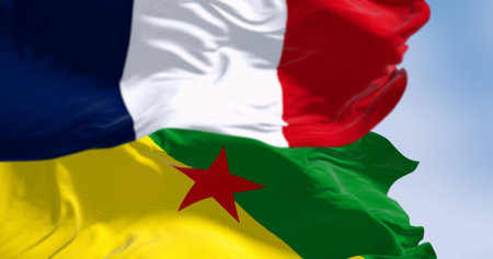 Flags of French Guiana and France waving in the wind on a clear day. Overseas department, region and single territorial collectivity of France. 3d illustration render. Selective focus. Rippling fabricの写真素材