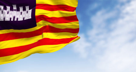 Balearic Islands flag waving in the wind on a clear day. Four red lines on yellow with white castle on purple canton. 3D illustration render. Rippling fabric. Selective focusの写真素材