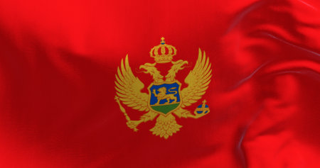 Close-up of national flag of Montenegro waving in the wind. Red with a golden border and features the national coat of arms in its center. 3d illustration render. Selective focus.の写真素材