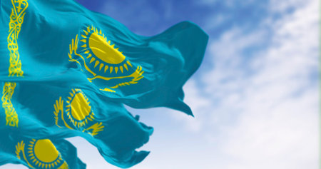 Kazakhstan national flags waving on a clear day. Light blue field with a yellow sun and flying eagle in the center and a yellow ornamental band. 3d illustration render. Rippling fabric.の写真素材