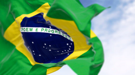Close-up of national flags of Brazil waving in the wind. Yellow diamond on green field with blue...