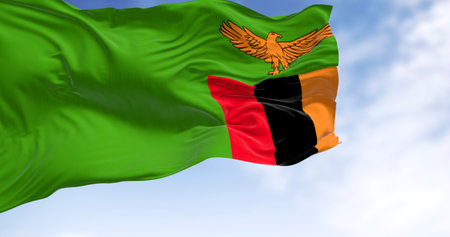 Zambia national flag waving in the wind. Green with an orange eagle in flight over a block of three vertical stripes in red, black, and orange. 3d illustration render. Selective focusの写真素材